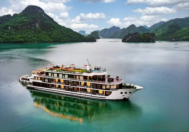 A three-deck cruise ship on calm water in Ha Long Bay