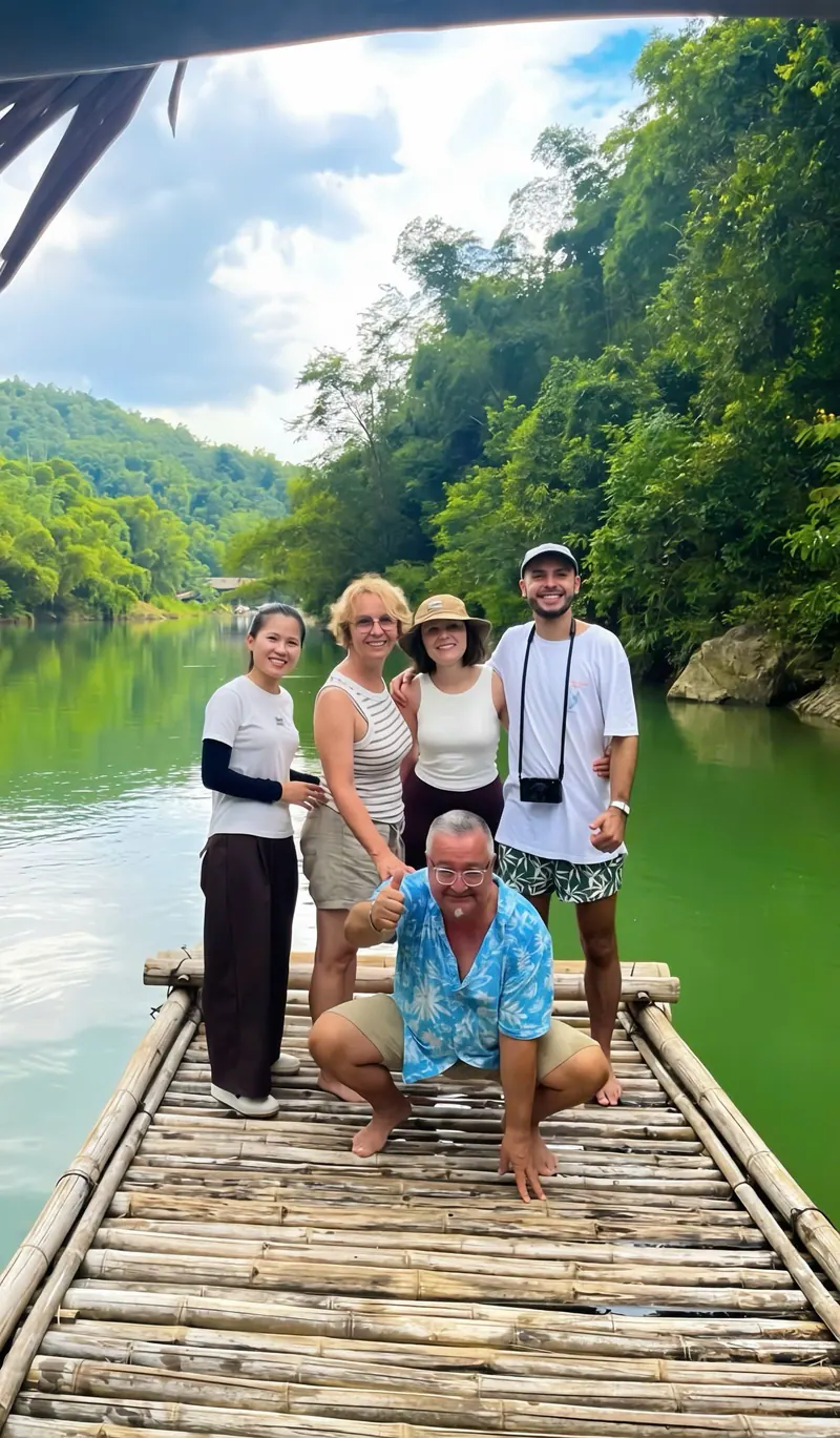 Travellers smiling on a bamboo raft on a jade-green river in Pu Luong